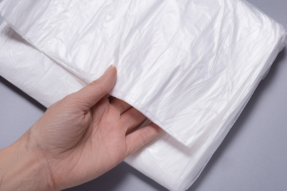 Single hand touching Polyethylene Plastic Sheet on gray background; temporary roof fixes for a leaking roof
